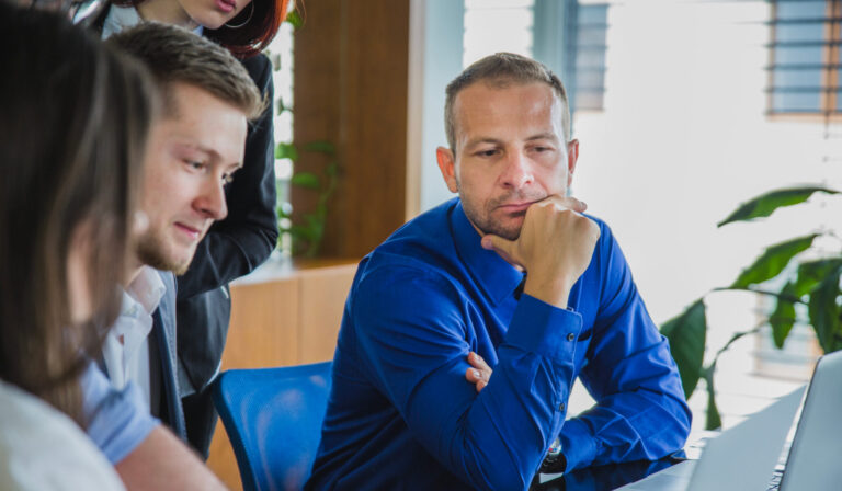 Man With Coworkers Thinking Scaled E1766063682250